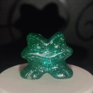 Figura Gogo Crazy Bones verde translúcido con purpurina sobre fondo oscuro, colocada sobre base blanca