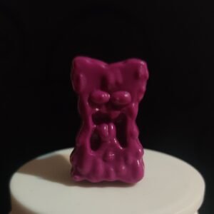 Figura original Gogo Crazy Bones color fucsia con diseño de expresión gruñona sobre fondo negro