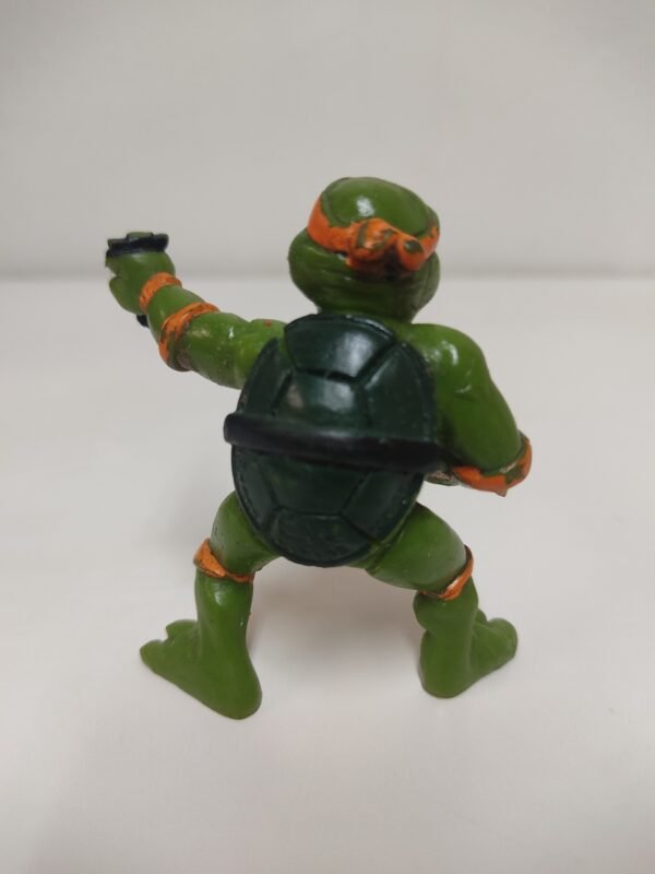 Vista trasera de figura Michelangelo TMNT con caparazón y antifaz naranja