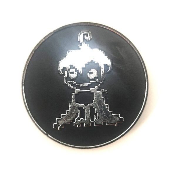 Tazo metálico negro con personaje estilo pixel art grabado en relieve brillante.